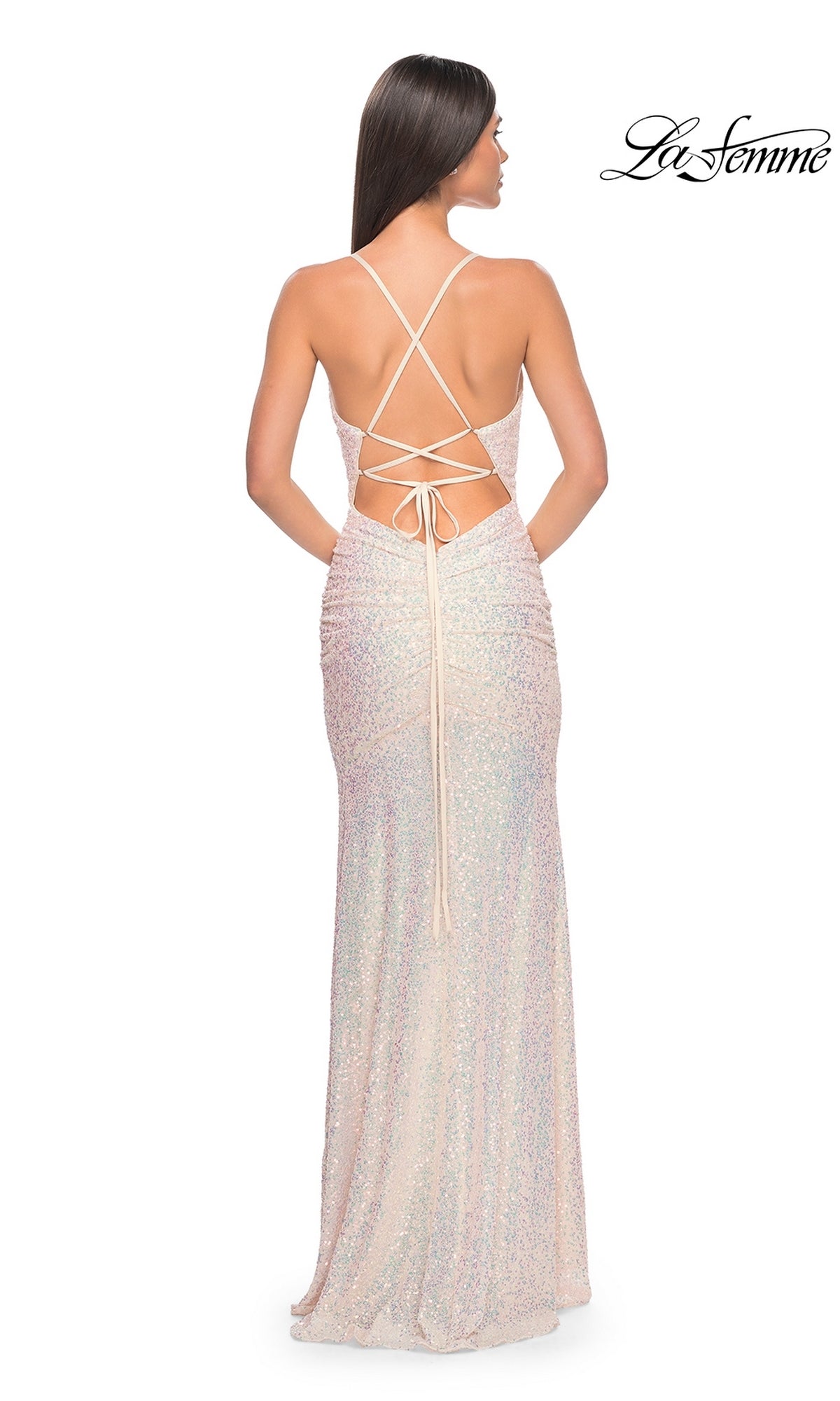 A woman stands facing away in the La Femme Tight Long Sequin Prom Dress 32331, a sparkling floor-length gown with an open crisscross lace-up back.